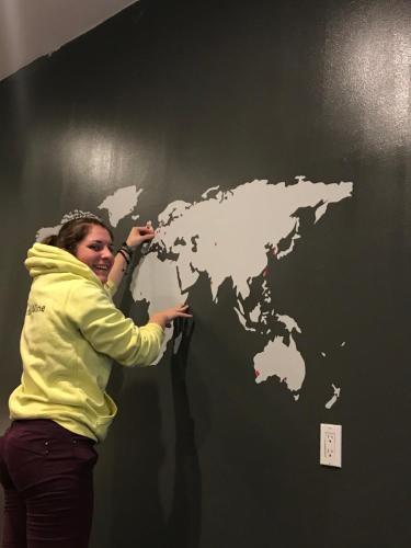 a woman is painting a world map on a wall at The Clarence Park in Toronto