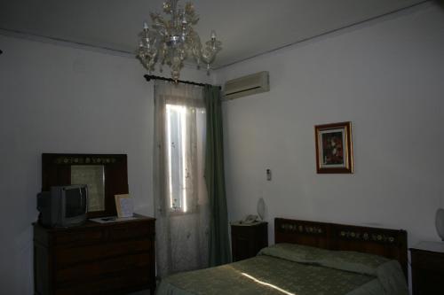 a bedroom with a bed and a television and a chandelier at Locanda Stella D'oro in Quinto di Treviso
