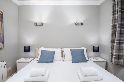 a bedroom with a large white bed with blue pillows at Ice Cream Suite in Edinburgh