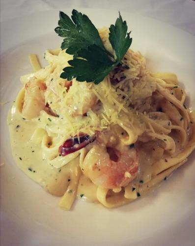 a plate of pasta with shrimp and a parsley garnishment at Cotswold Gardens in Armidale