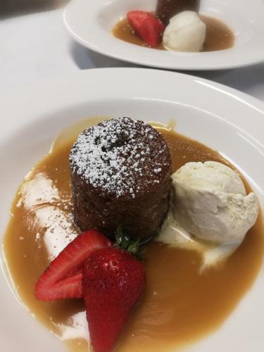a dessert with strawberries and ice cream on a plate at Cotswold Gardens in Armidale