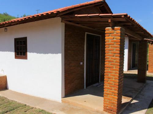 Casa blanca pequeña con techo de madera en Chalés Cachoeira Cafundó, en Bueno Brandão