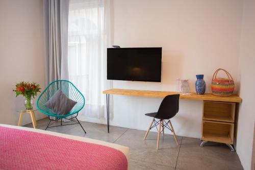 a living room with a tv and two chairs at Hotel Mamá Carlota in Querétaro