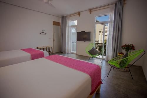 a hotel room with two beds and a balcony at Hotel Mamá Carlota in Querétaro