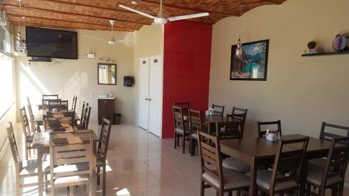 a restaurant with wooden tables and chairs and a red wall at Hotel Gesa in Villa Corona