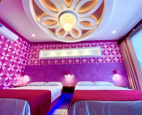 two beds in a purple room with a large ceiling at Hotel Boutique TEKALI INN in Cuetzalán del Progreso