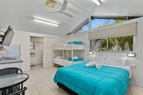 a bedroom with a blue bed and a kitchen at Tasman Holiday Parks - Torquay Palms in Hervey Bay
