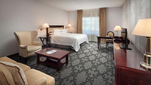 a hotel room with a bed and chairs and a table at Anaheim Majestic Garden Hotel in Anaheim