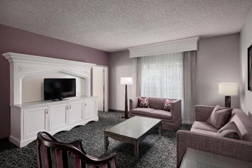 a living room with a tv and a couch and chair at Anaheim Majestic Garden Hotel in Anaheim