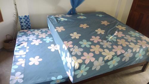 a bed with a blue cover with flowers on it at pemuyan mirissa70 in Mirissa