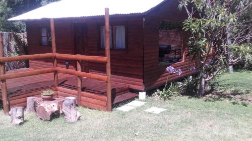 a log cabin in the yard with a porch at Cabaña El Cristo in La Cumbre