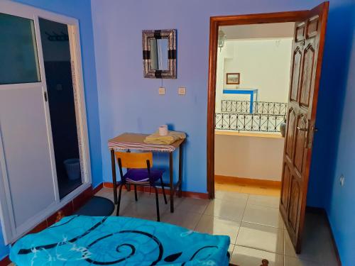 Cette chambre dispose d'une table, d'une petite table et d'une porte. dans l'établissement Dar Bleu Pearl, à Chefchaouen
