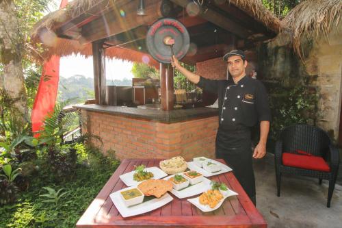 a man in uniform standing next to a table with food at Jungle Retreat by Kupu Kupu Barong in Ubud