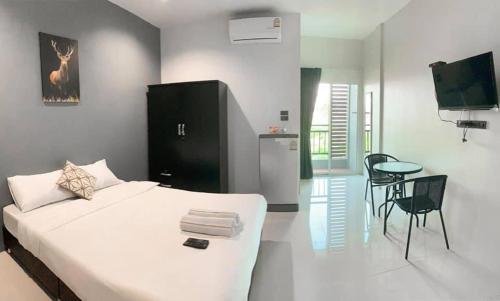 a bedroom with a bed and a table and a television at Kiirin House in Ban Pong