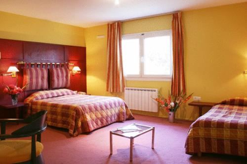 a hotel room with two beds and a table at Les Colonnes Strasbourg Zenith in Strasbourg