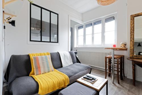 - un salon avec un canapé gris et une couverture jaune dans l'établissement La Trouv, à Trouville-sur-Mer