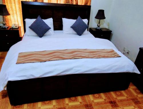 a bedroom with a large bed with white sheets and blue pillows at Pyramid International Guest House in Islamabad
