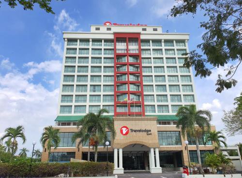 a large hotel with a red building with palm trees at Travelodge Ipoh in Ipoh