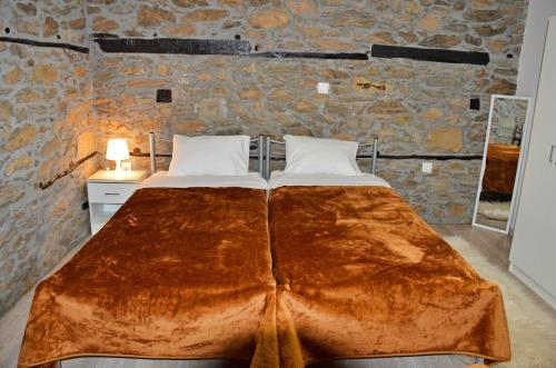 a large bed in a room with a stone wall at Stone Villa "To Petrino" in Florina