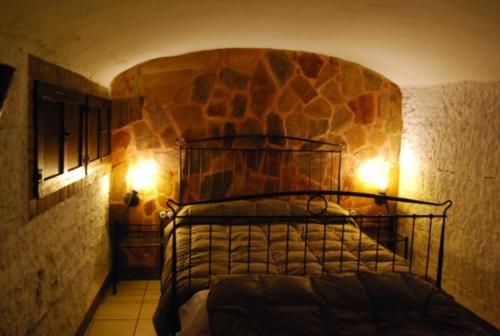 um quarto com uma cama com uma parede de pedra em Cueva El Haro em Baza