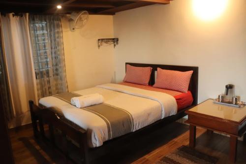 a bedroom with a bed with red pillows and a table at Coorg North Breeze Homestay in Madikeri