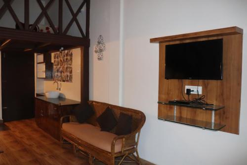 a living room with a chair and a flat screen tv at Coorg North Breeze Homestay in Madikeri