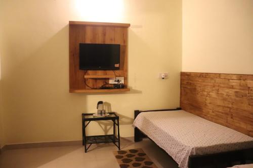 a bedroom with a bed and a tv on the wall at Coorg North Breeze Homestay in Madikeri