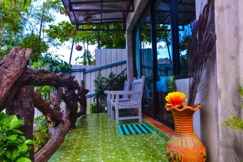 a porch with a chair and a vase with flowers in it at Baan Tubkaek Hotel in Tab Kaek Beach