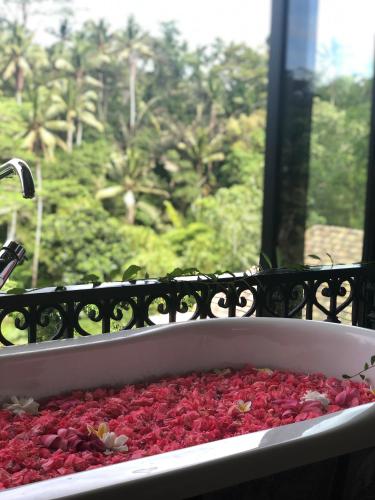 a bath tub filled with red flowers next to a window at Puri Kasih Gottlieb in Ubud