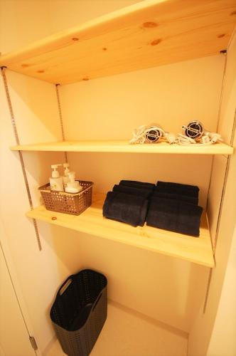 a wooden shelf with towels and a basket on it at 西条ゲストハウス八反 in Higashihiroshima