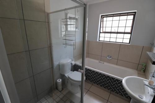 a bathroom with a toilet and a tub and a sink at Carole's Cottage in Hermanus