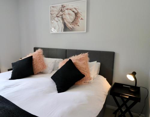 a bed with black and white pillows on it at Carole's Cottage in Hermanus