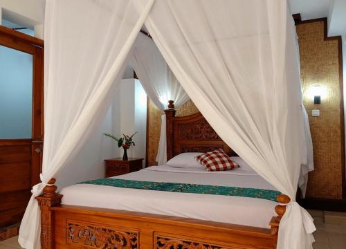 Schlafzimmer mit Himmelbett und weißen Vorhängen in der Unterkunft KARANG SARI Guesthouse in Munduk