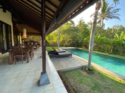 a patio with a table and a swimming pool at Rumah Dadong in Ubud