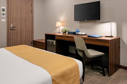 a hotel room with a bed and a desk with a television at Golden Season Hotel in Ninh Binh