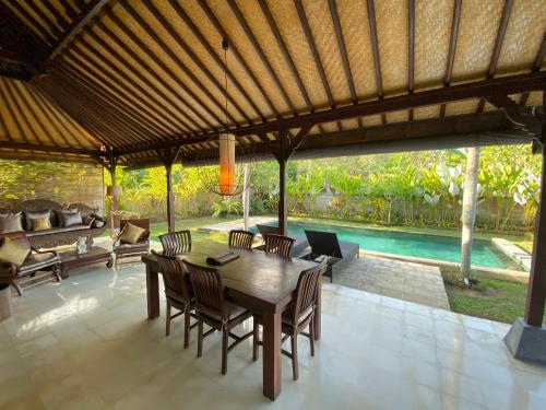 a dining room with a table and chairs and a pool at Rumah Dadong in Ubud