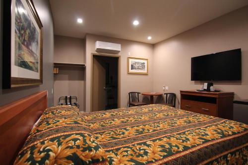 a hotel room with a bed and a flat screen tv at Dunes Inn - Wilshire in Los Angeles