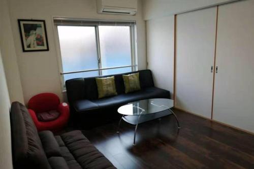 a living room with a black couch and a red chair at 駅近-最大収容9人JR小岩駅まで徒歩圏Leo小岩301 in Tokyo