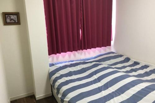 a bedroom with a striped bed with a window at 駅近-最大収容9人JR小岩駅まで徒歩圏Leo小岩301 in Tokyo