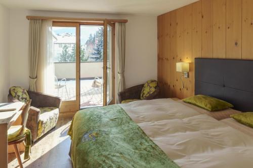 a bedroom with a large bed and a large window at Hotel Saluver in Celerina