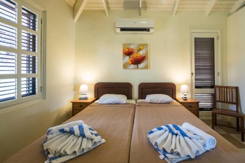two twin beds in a room with two windows at Blue Bay Beach Villa at Pool and Golfcourse in Blue Bay