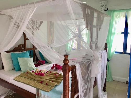 a bedroom with a canopy bed with flowers on it at Driftwood Beach Lodge in Jambiani