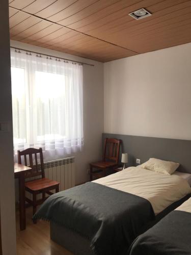 a bedroom with a bed and two chairs and a window at Pokoje do wynajęcia Magdalena Nowak in Krynica Zdrój