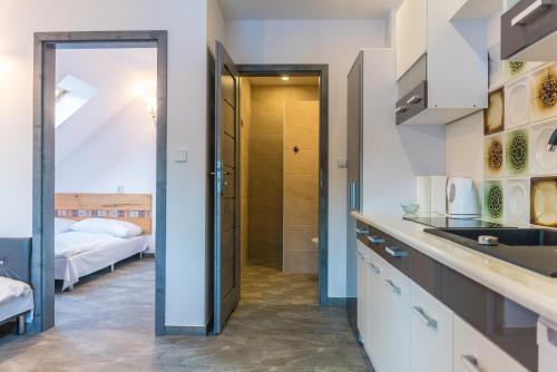a kitchen with a sink and a room with a bed at Apartamenty pod Gromadzyniem in Ustrzyki Dolne