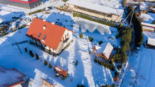 a house with a red roof in the snow at Apartamenty pod Gromadzyniem in Ustrzyki Dolne