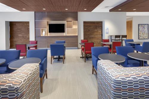 a waiting room with tables and blue chairs at Holiday Inn Express & Suites - Hudson I-94 by IHG in Hudson
