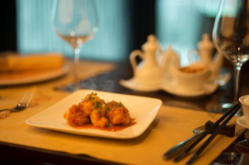a plate of food on a table with wine glasses at Taj Palace, New Delhi in New Delhi