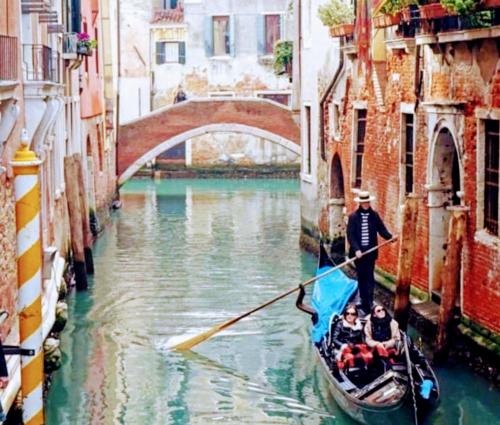 a man is rowing a gondola down a canal at Villa Stefania in Noventa Padovana