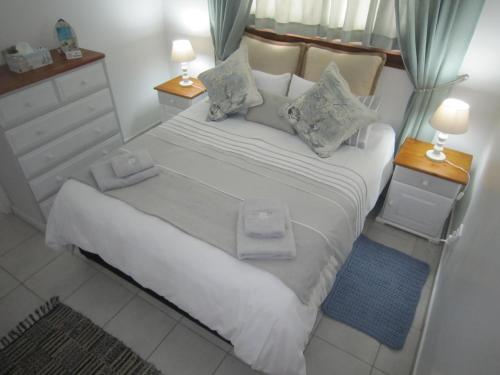 um quarto com uma grande cama branca com duas mesas de cabeceira em See Rus Self catering unit in Westbrook KZN Private Neat and Cosy em Westbrook