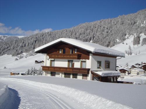 a building covered in snow with a road in front at Haus Annemarie Apartments Kartitsch - Hochpustertal in Kartitsch